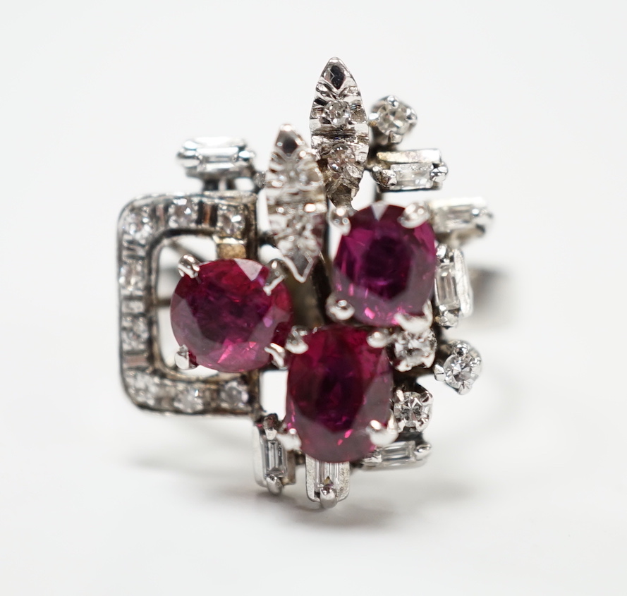 A recent 18k white metal, ruby and diamond cluster set modernist dress ring, size N/O, gross weight 5.7 grams.